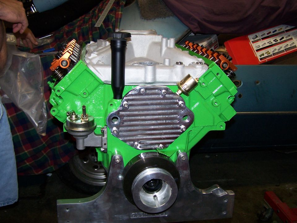 Bright green rebuilt V8 engine with aluminum timing cover on a stand