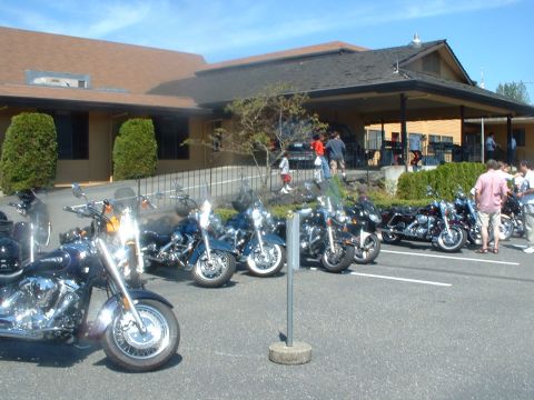1999 Ford Crown Victoria - A group of motorcycles are parked in a lot outside a building during what appears to be a show.