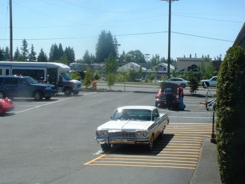 1999 Ford Crown Victoria - Classic 1964 Impala parked in a lot, other vehicles visible in the background.