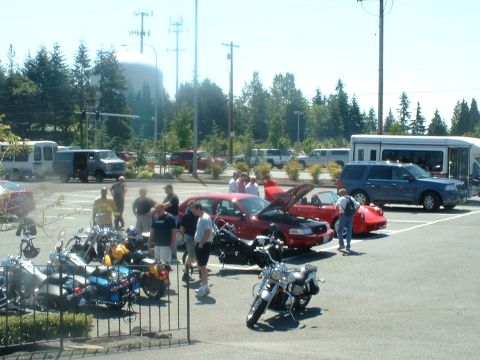 1999 Ford Crown Victoria - A gathering of vehicles, including motorcycles and cars, in an outdoor parking area on a sunny day.