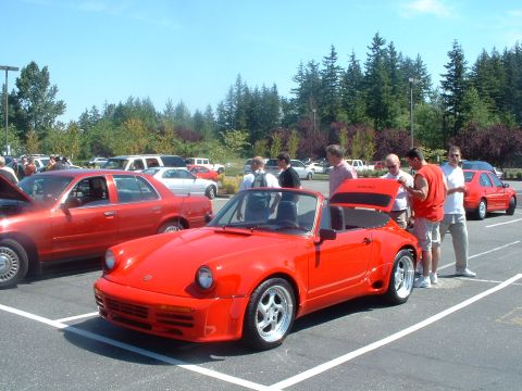 1999 Ford Crown Victoria - A red convertible sports car is parked at an outdoor car show with several other vehicles visible.