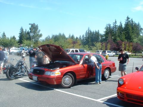 1999 Ford Crown Victoria - A red 1999 Ford Crown Victoria is displayed with its hood open at an outdoor car show.