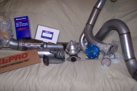 1997 Ford Probe - Various automotive parts are laid out on a surface, including exhaust components and engine accessories.