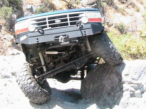 1994 Ford Bronco - This 1994 Ford Bronco is navigating a difficult off-road obstacle, with its tires positioned on large rocks.