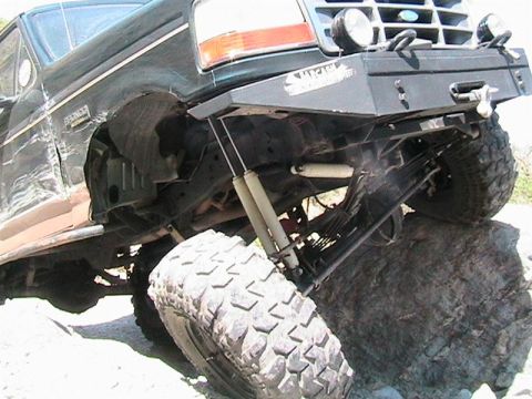 1994 Ford Bronco - Modified Ford Bronco with off-road tires navigates a large rock obstacle.