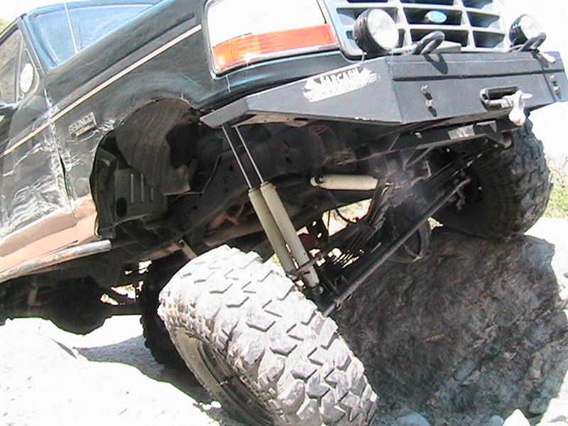 Dark green Ford Bronco with lifted suspension and large tires on a rock