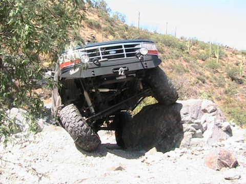 1994 Ford Bronco - This 1994 Ford Bronco is shown tackling a challenging off-road course with one wheel on a large rock.