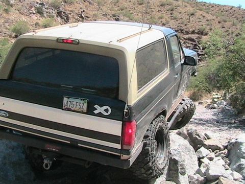 1994 Ford Bronco - A Ford Bronco navigates a rocky trail in a desert environment.