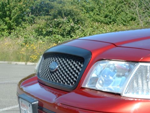 1999 Ford Crown Victoria - Close-up of the front grille and headlight assembly on a red Ford Crown Victoria.