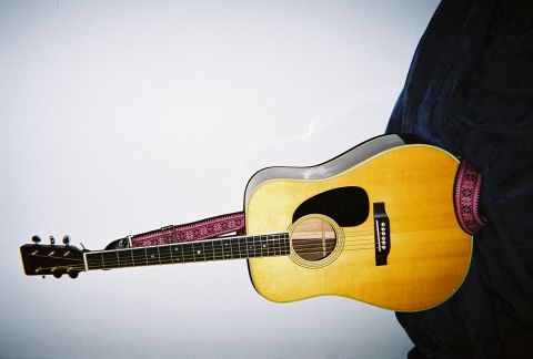 1972 Ford Ranchero - An acoustic guitar rests against a dark fabric, its natural wood finish highlighted by a decorative strap.