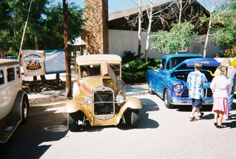 1972 Ford Ranchero - A gold 1929 Ford Model A coupe is parked next to a blue pickup truck at a car show.