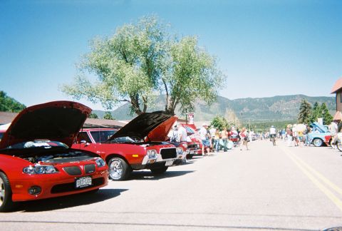 1972 Ford Ranchero - A sunny day car show with multiple vehicles on display and spectators enjoying the event.