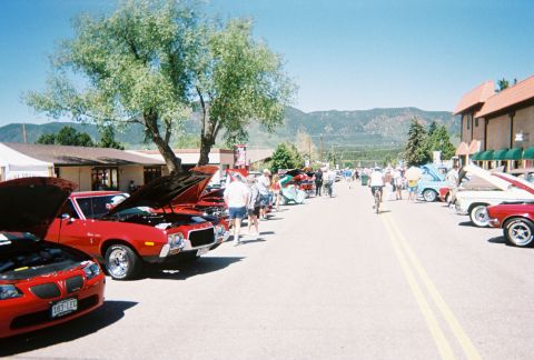 1972 Ford Ranchero - A street lined with classic cars and people enjoying a sunny day at an outdoor car show.