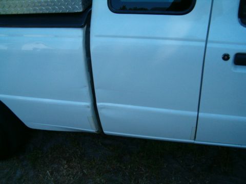 1991 Ford Bronco - Side view of a white pickup truck with visible body damage and a diamond plate toolbox mounted in the bed.