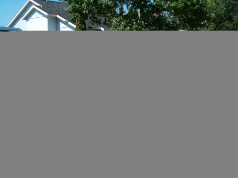 1991 Ford Bronco - A white SUV is parked in front of a residential home on a sunny day.