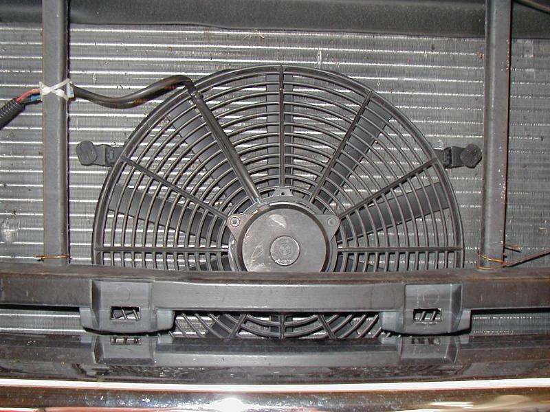 Black electric cooling fan mounted on a radiator with wiring harness