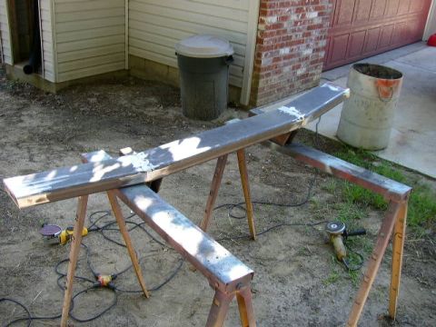 1995 Ford Bronco - Metal bumper part being worked on outdoors with tools and sawhorses.