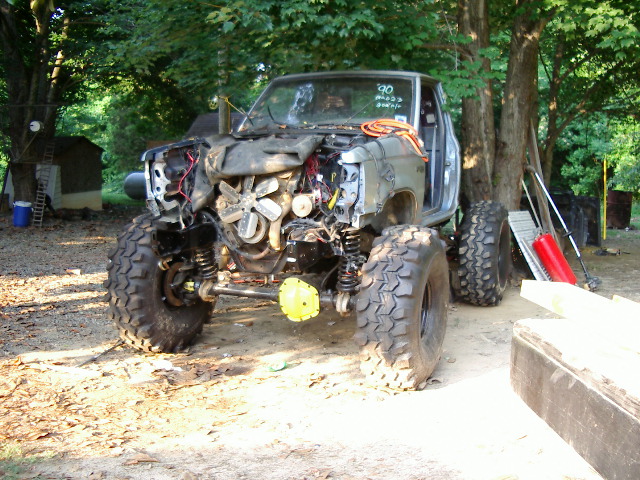 Off-road truck with front end removed, showing engine and suspension. Big tires are mounted