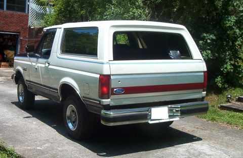 1991 Ford Bronco - This Ford Bronco is parked in front of a brick house with trees in the background.