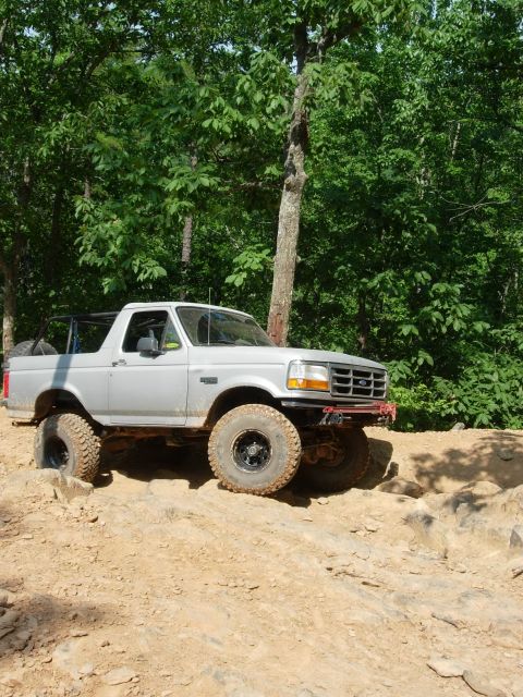 1995 Ford Bronco - Silver 1995 Ford Bronco navigating an off-road trail with large tires.