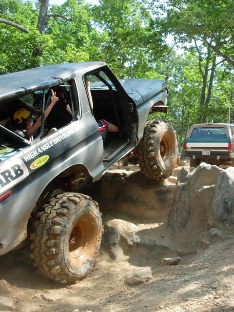 1995 Ford Bronco - A heavily modified Ford Bronco tackles an off-road obstacle course with another SUV in the background.