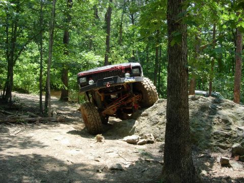 1995 Ford Bronco - This modified Jeep Cherokee XJ navigates a challenging rocky obstacle on an off-road trail.