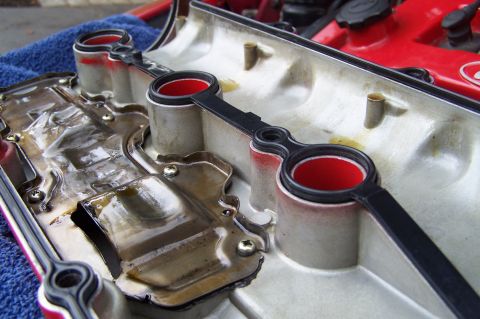 1997 Ford Probe - Close-up of a valve cover gasket with red seals and oil residue, showing internal engine components.