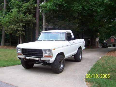1979 Ford Bronco - A white 1979 Ford Bronco pickup truck is shown from a three-quarter front angle on a paved surface.