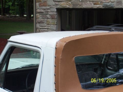1979 Ford Bronco - The side profile of a white 1978 Ford Bronco reveals its distinctive brown soft top construction.