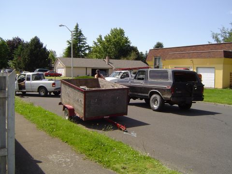 1979 Ford Bronco - A dark 1979 Ford Bronco is seen from the rear, towing a trailer down a residential street.
