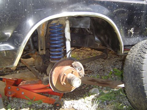 1979 Ford Bronco - The rear suspension and brake assembly of a vehicle are visible, supported by a jack.
