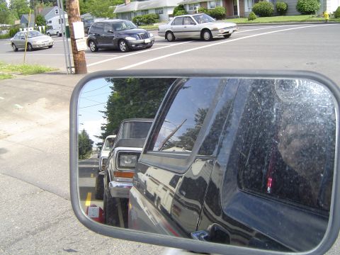1979 Ford Bronco - A line of vehicles, including two Ford Broncos, seen from the perspective of a side mirror.