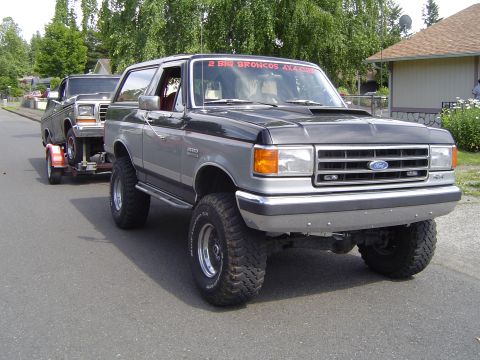1979 Ford Bronco - A modified Ford Bronco tows another vehicle, with a "2 Big Broncos 4x4 Club" banner visible on the windshield.