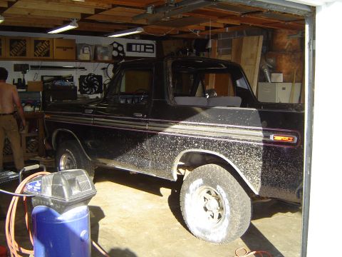 1979 Ford Bronco - This black Ford Bronco is parked inside a garage with tools and shelves visible.