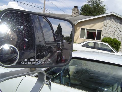1979 Ford Bronco - Side mirror reflection of a black SUV and a residential street scene.