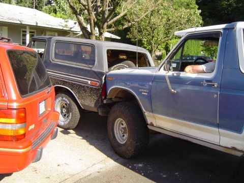 1979 Ford Bronco - Two Ford Broncos are parked side-by-side, with a red SUV in the foreground.