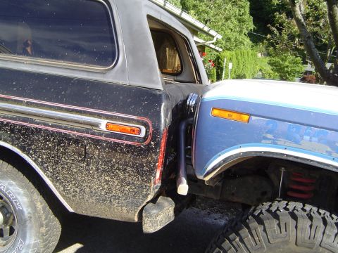 1979 Ford Bronco - Two SUVs are parked side-by-side, with the front of one vehicle nearly touching the rear of the other.