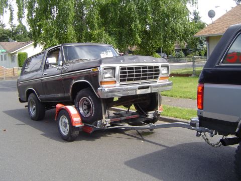 1979 Ford Bronco - A black 1979 Ford Bronco is being towed on a trailer by another vehicle.