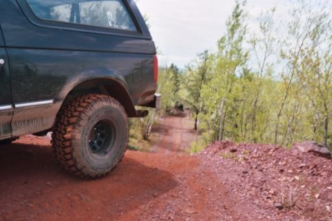 1996 Ford Bronco - 1996 Ford Bronco driving on a dirt road through a wooded area.