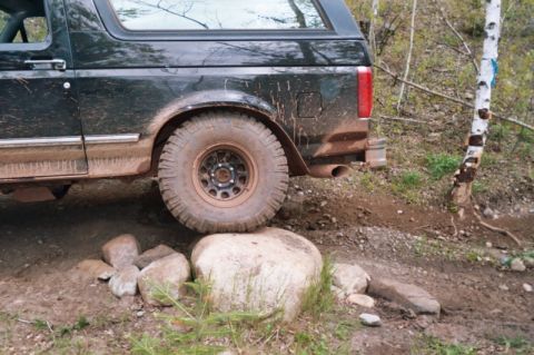1996 Ford Bronco - This dark green 1996 Ford Bronco navigates a rocky trail, demonstrating its off-road capability.