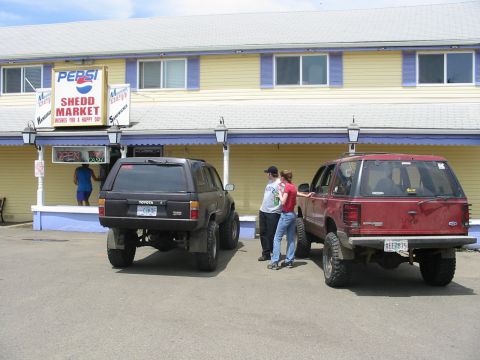 1991 Ford Explorer - Two SUVs are parked in front of a market with a Pepsi sign. One is a red Ford Explorer and the other is a black Toyota.