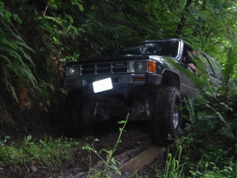 1991 Ford Explorer - A black Toyota 4Runner navigates a challenging off-road trail surrounded by lush green vegetation.