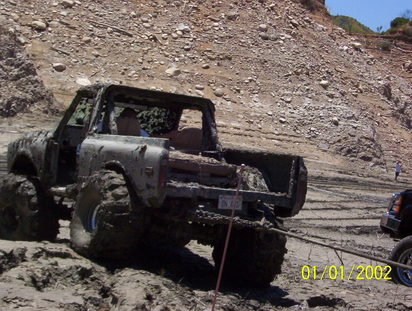 Muddy off-road truck stuck in mud, being pulled by another vehicle. Date stamp reads 01/01/2002