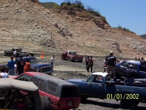 1985 Ford Bronco - Multiple trucks are bogged down in mud during an off-road event. The date 01/01/2002 is visible.