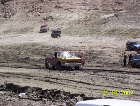 1985 Ford Bronco - Several vehicles are stuck in the mud on a dry, rocky hillside. A date stamp shows 01/01/2002.