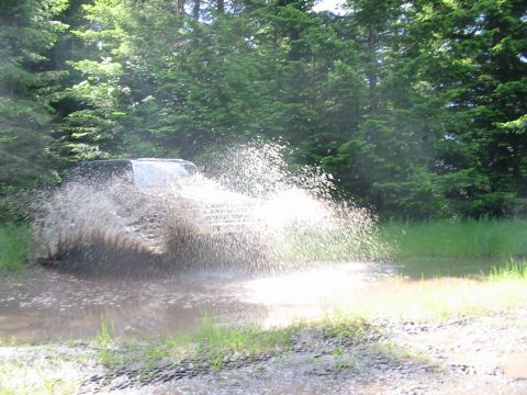1991 Ford Explorer - A 1991 Ford Explorer navigates a muddy obstacle during a trip.