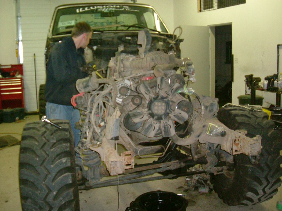 1995 Ford F-150 engine bay with mechanic working on it, large tires visible