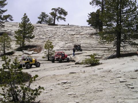 1989 Ford Bronco - Multiple off-road vehicles traverse a challenging rocky landscape under a cloudy sky.