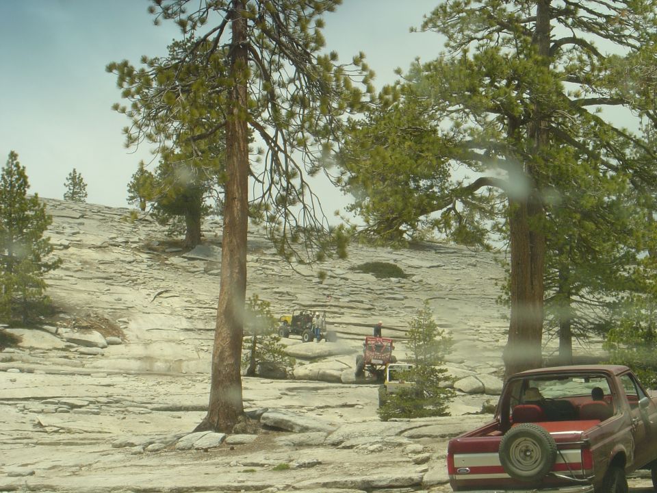 Red pickup truck rear view with spare tire. Off-roading scene with multiple vehicles