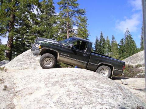 1989 Ford Bronco - Dodge Ram 1500 V8 pickup truck navigating rocky terrain off-road.